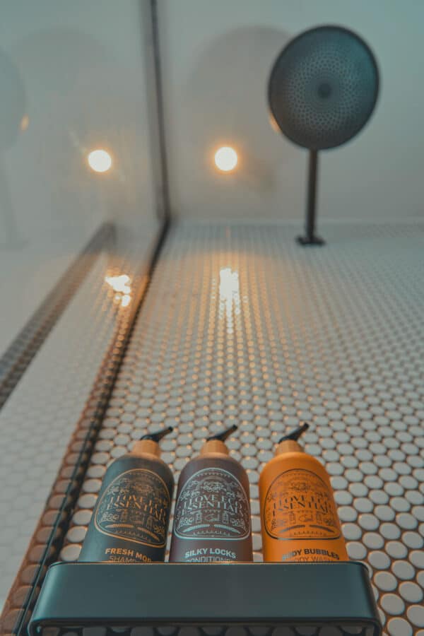 Close-up of Eco Essentials toiletries in the walk-in rain shower – eco-conscious shower experience at John & Will Bremen