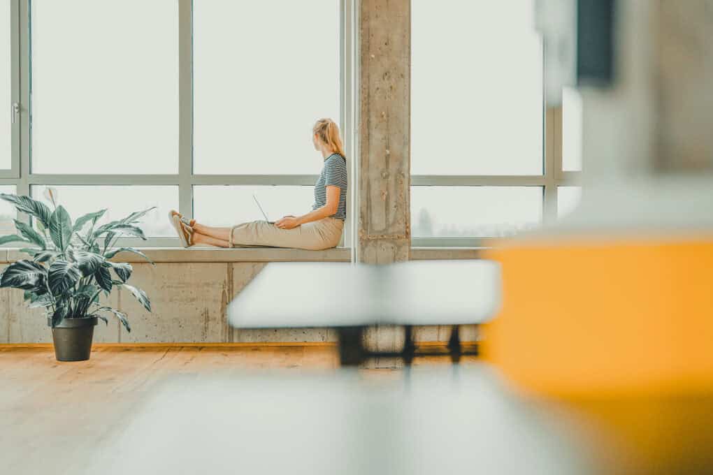 Woman sitting on the windowsill at Boven 7 event space in the John & Will hotel, gazing outside