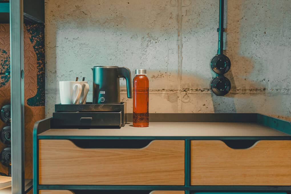 Room detail at John & Will hotel – designer sideboard with kettle and the red John & Will bottle for free water refills