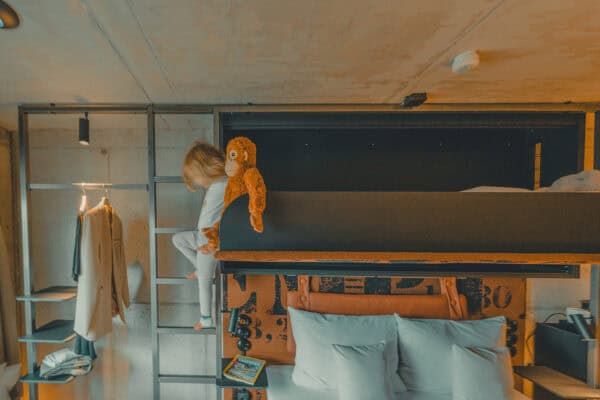 Lütt Stuuv – child climbing the ladder of the fold-out crib in the cozy two-person room at the John & Will Hotel.