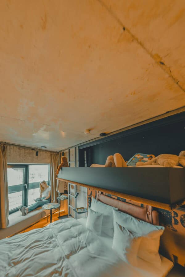 Relaxed family moment in the Lütt Stuuv – sustainable silo room with window seat and extra bed for kids at John & Will Bremen