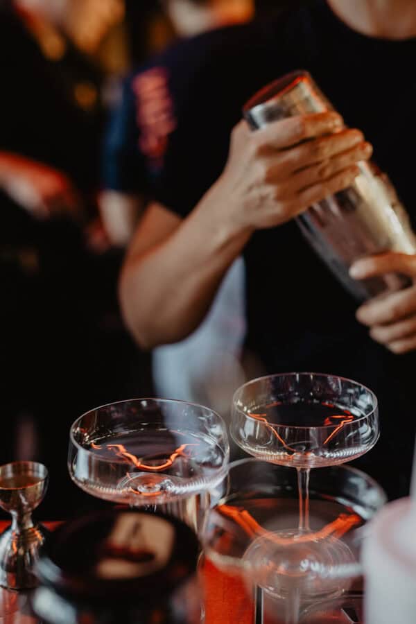Two cocktail glasses on the counter at a wedding celebration in the John & Will hotel Bremen – blurred hands with shaker in the background