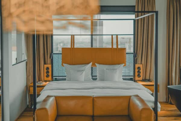 Cozy leather sofa in the Toorn Stuuv at John & Will Bremen with an double bed visible in the background of the stylish suite