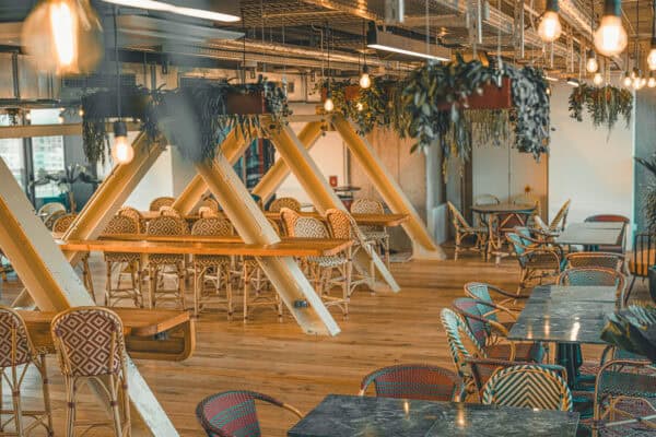 Inviting interior of the rooftop Dachstuuv at the John & Will Hotel Bremen – modern industrial design meets warm wooden elements, hanging plants, and cozy seating areas. Ideal for social evenings or relaxed meals with a view over Bremen’s Überseestadt.
