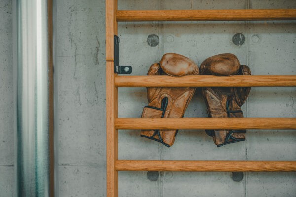 Detail shot: leather boxing gloves on a wooden wall bar.
