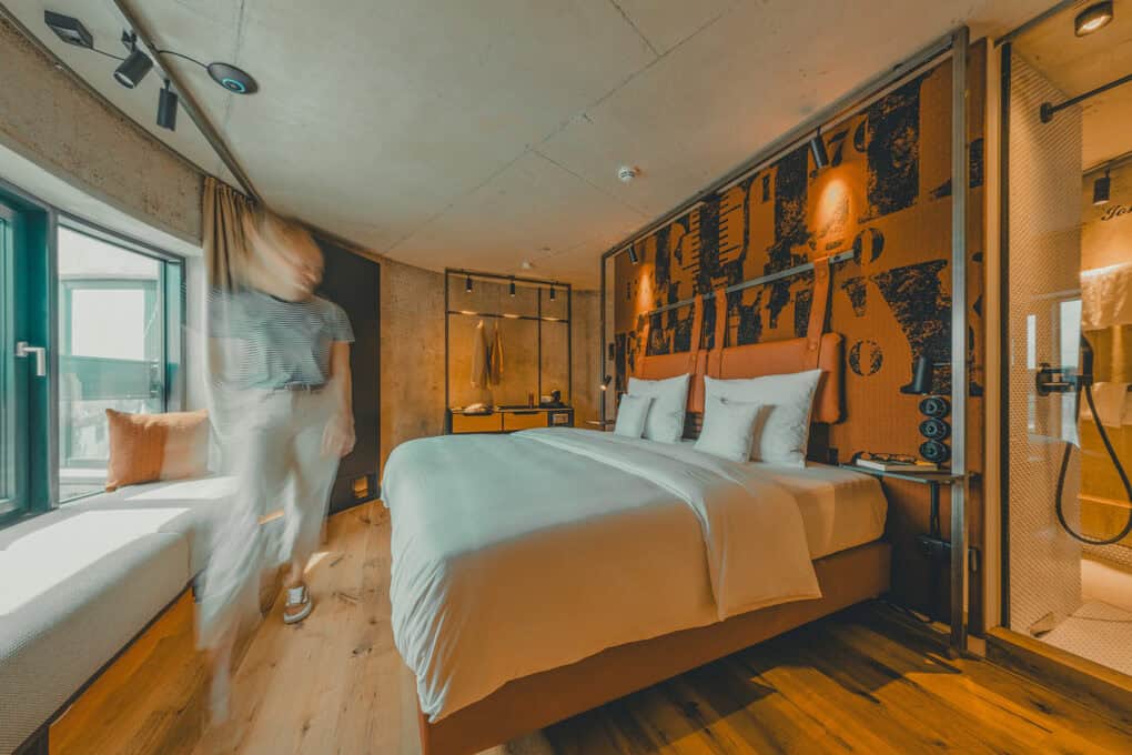 Grode Stuuv im John & Will Hotel Bremen – 24 m² großes Zimmer mit Doppelbett und Fenstersitzbank, eine Frau geht in der Unschärfe durchs Bild