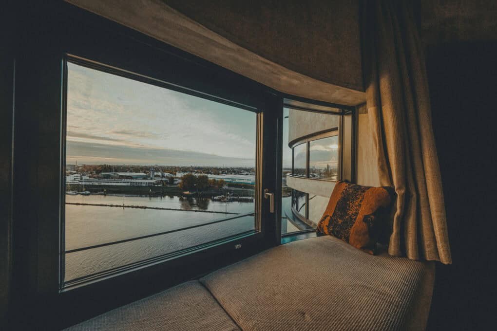 Weserblick aus dem Fenster eines Zimmers im John & Will Silo-Hotel by Guldsmeden – Kissen auf der Fenster-Sitzbank, Abendstimmung über der Weser