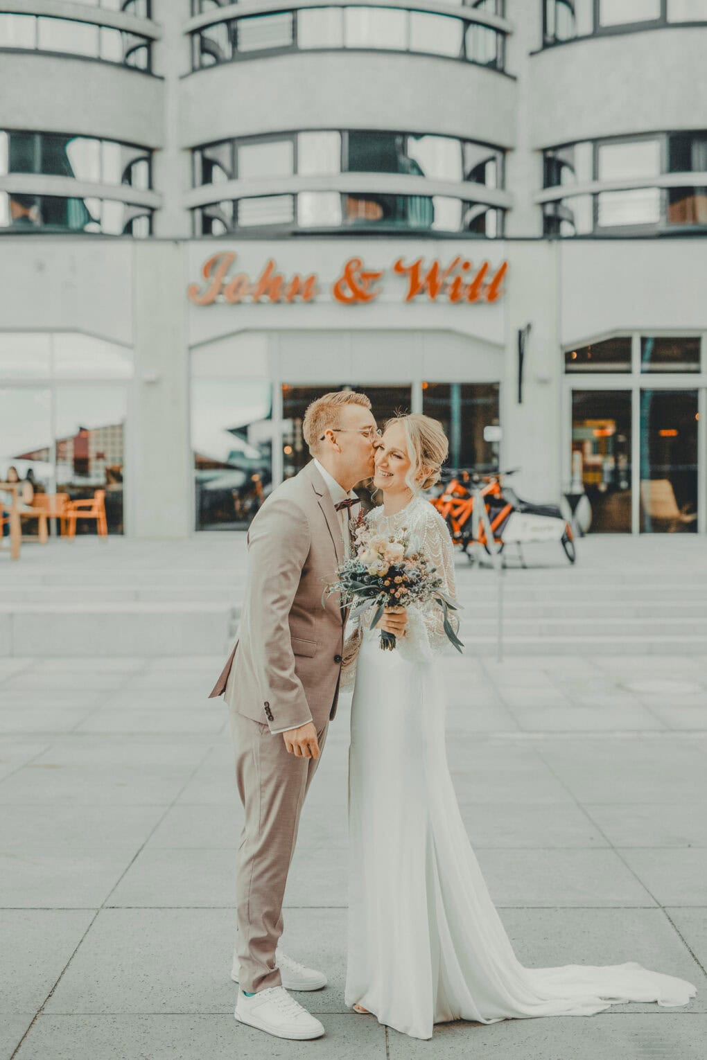 Hochzeitspaar posiert vor dem Eingang des John & Will Hotels in Bremen – urban heiraten mit Persönlichkeit und Design