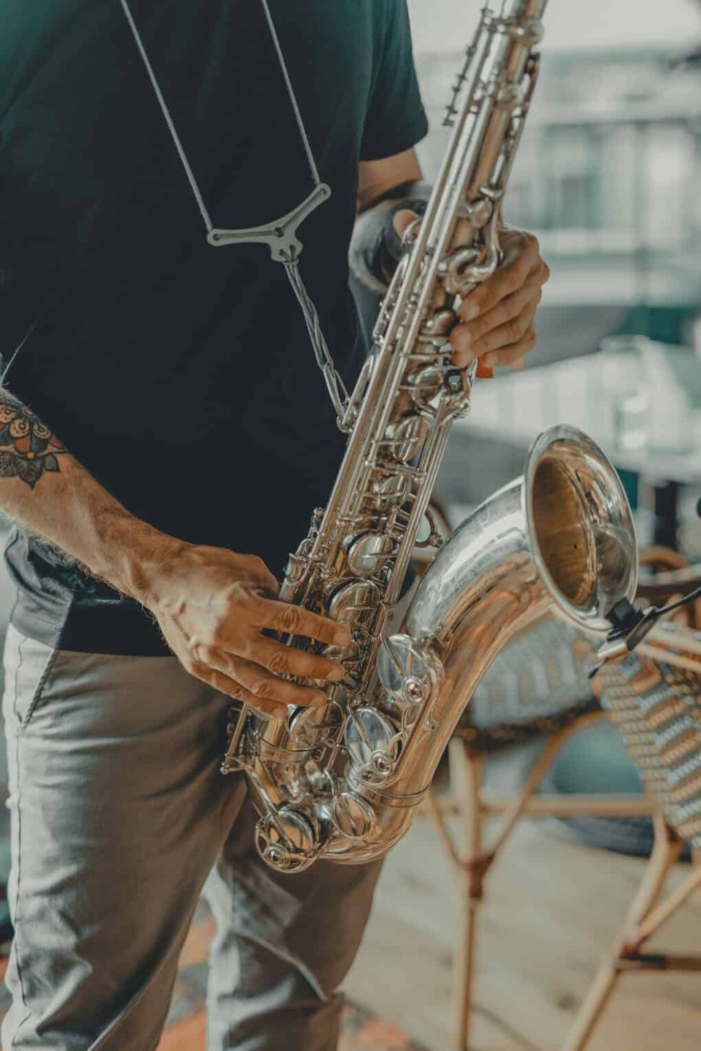 Mann mit Tätowierung und schwarzem T-Shirt spielt Saxofon im stilvollen Ambiente eines modernen Veranstaltungsortes, passend für Livemusik-Events im John & Will Silo-Hotel Bremen.