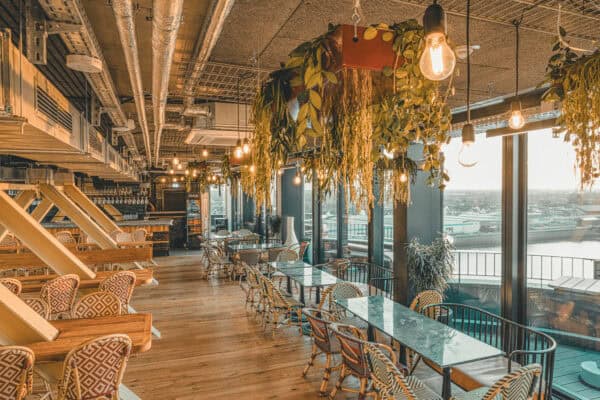 Innenansicht der Dachstuuv im John & Will Hotel Bremen stilvolle Kombination aus Industrial Design, Pflanzen-Elementen und gemütlicher Einrichtung mit Panoramablick auf die Weser. Perfekte Location für Frühstück, Dinner oder Sundowner in der Bremer Überseestadt.