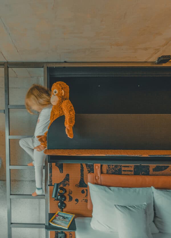 Kind klettert mit ihrem Kuscheltier-Affen in der Hand aus dem Ausklappbett in der LüttStuuv.