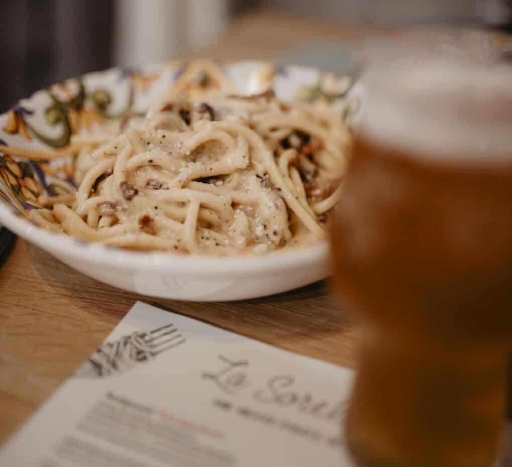 Foto mit einem Teller Pasta sowie einem Glas Bier in dem Restaurant La Sorella di Manu